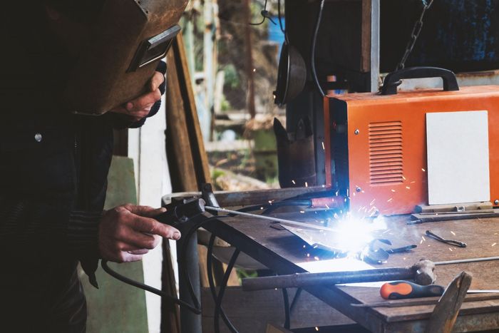 A man is welding a piece of metal on a table.