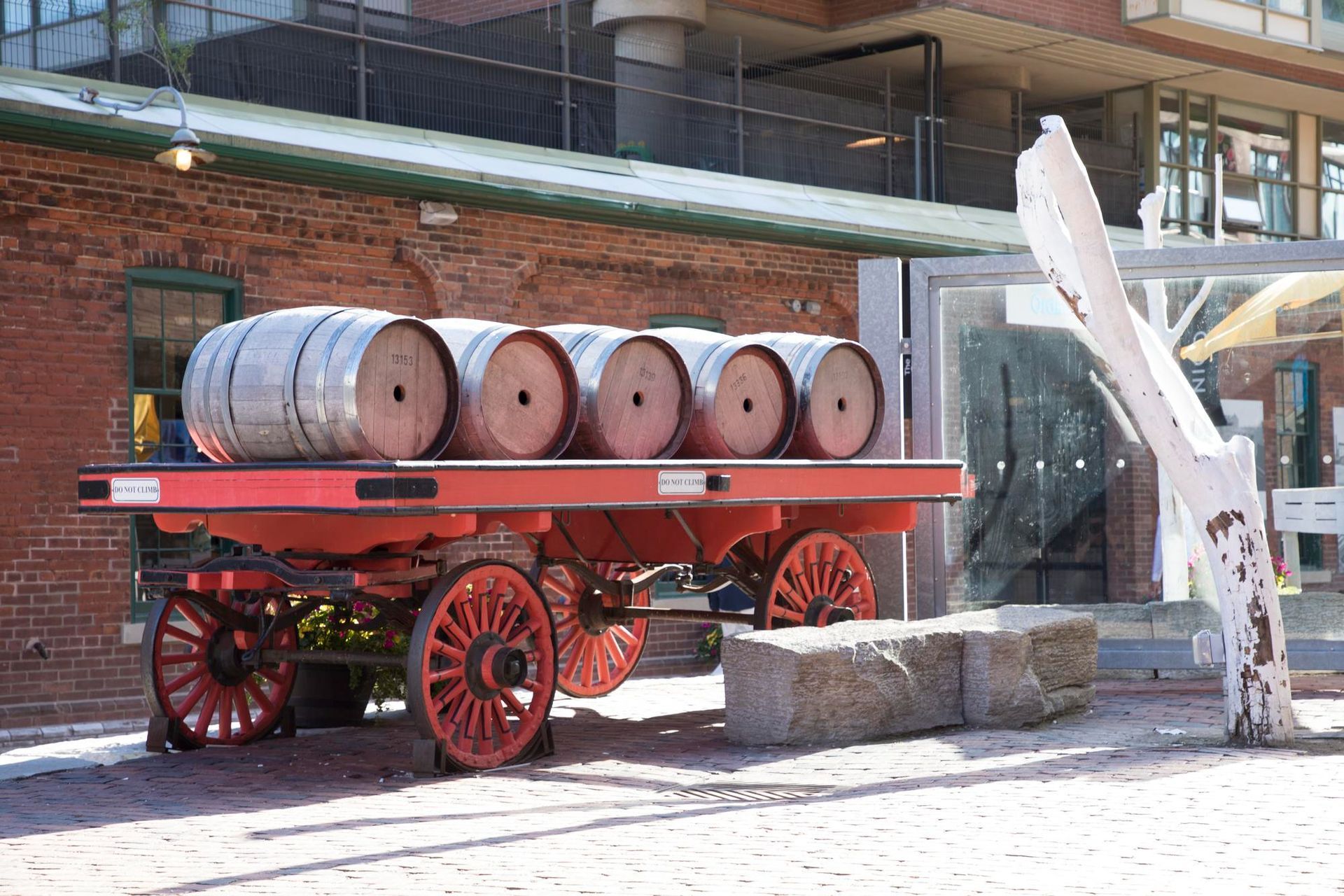 A wagon with barrels on it is parked in front of a brick building.