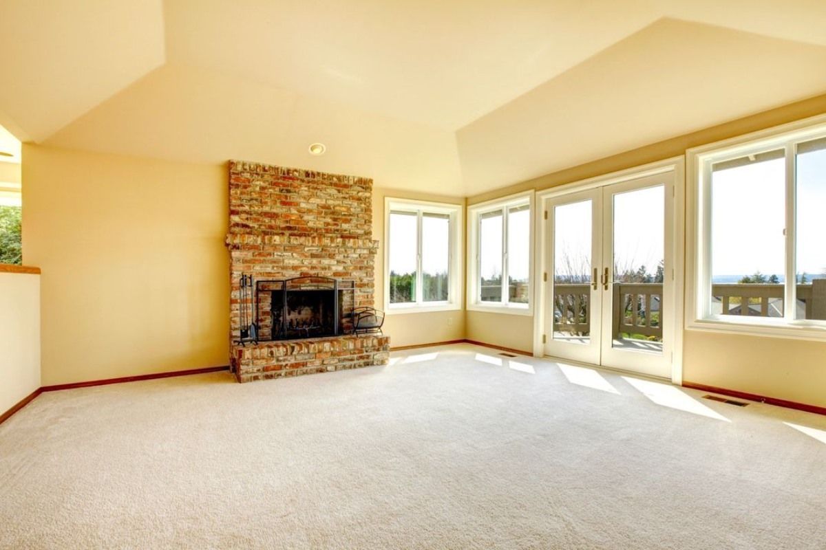 an empty living room with a fireplace and lots of windows .