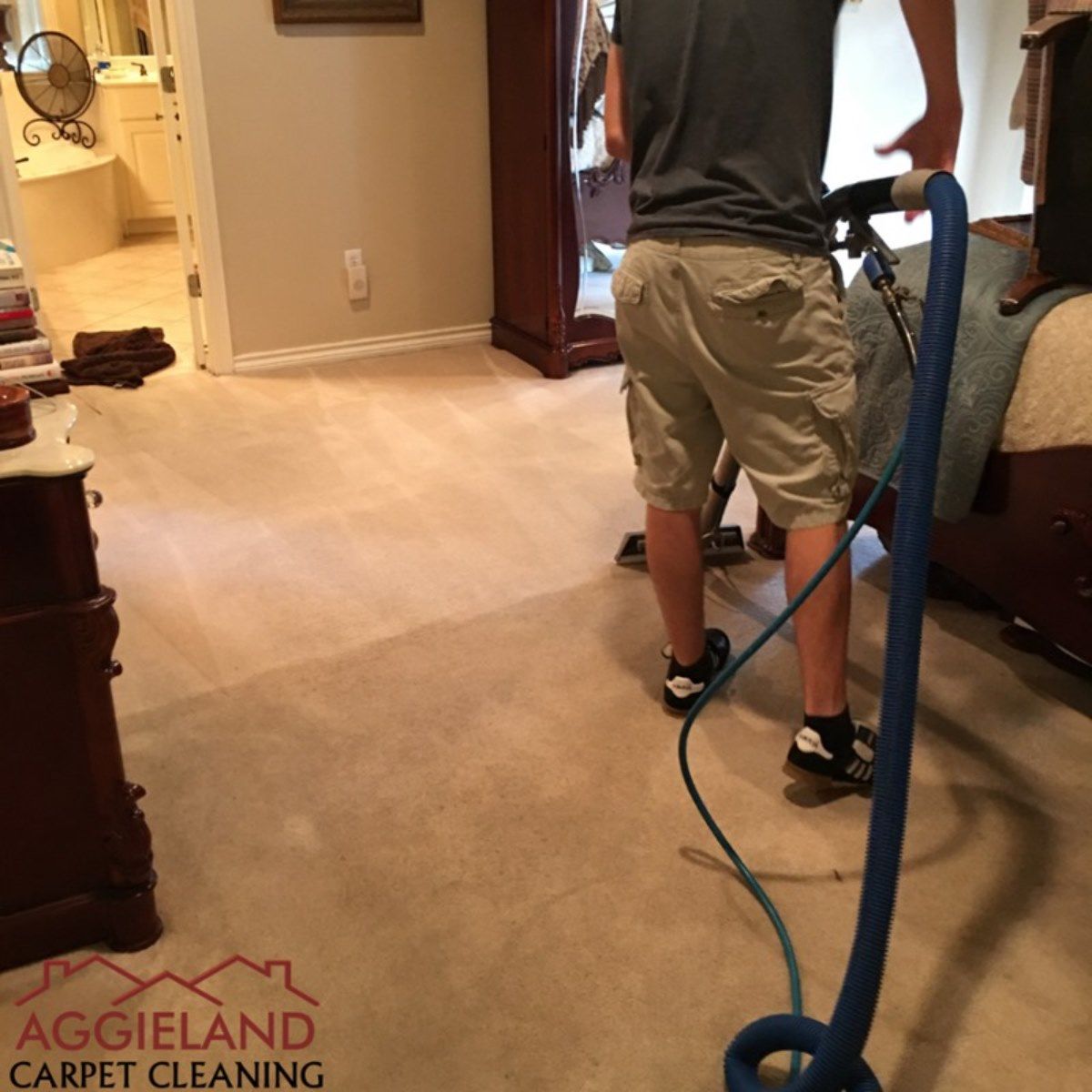 a man is using a vacuum cleaner in a bedroom sponsored by aggieland carpet cleaning