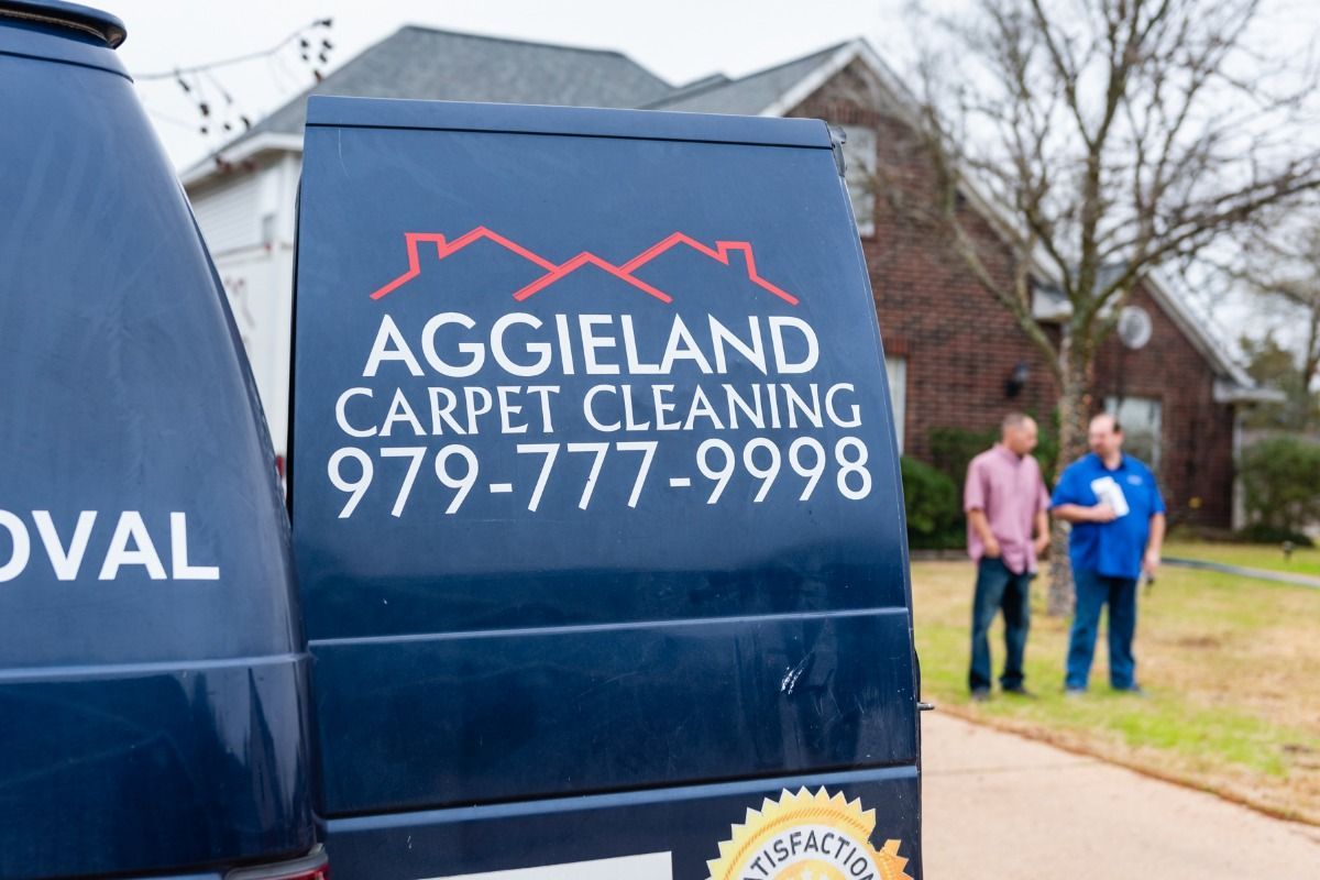 two aggieland carpet cleaning vans are parked in front of a house