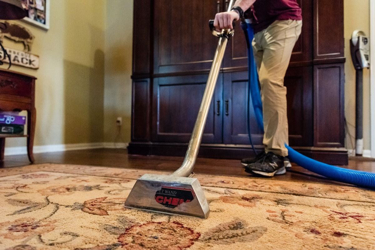 a man is using a vacuum cleaner to clean a rug in a living room .