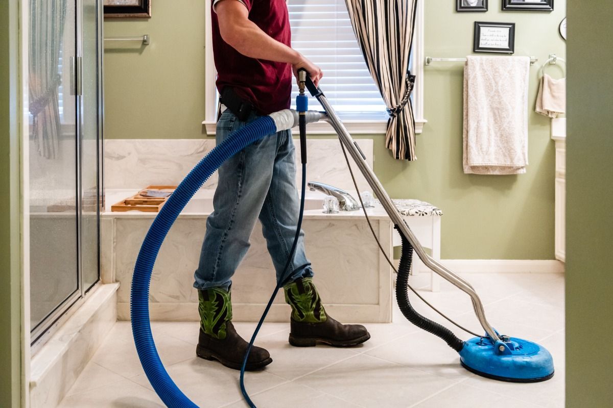 a man is cleaning a bathroom floor with a vacuum cleaner .
