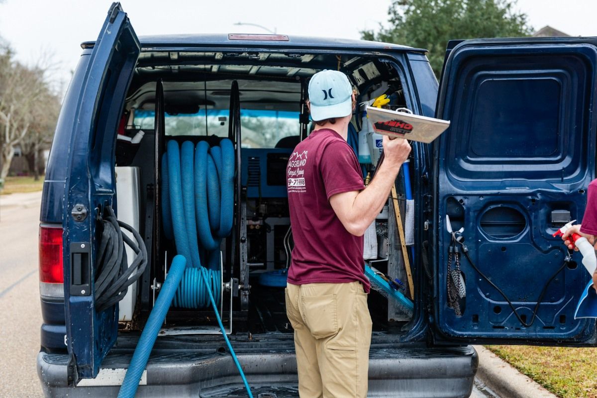 a man is standing in the back of a blue van holding a clipboard .