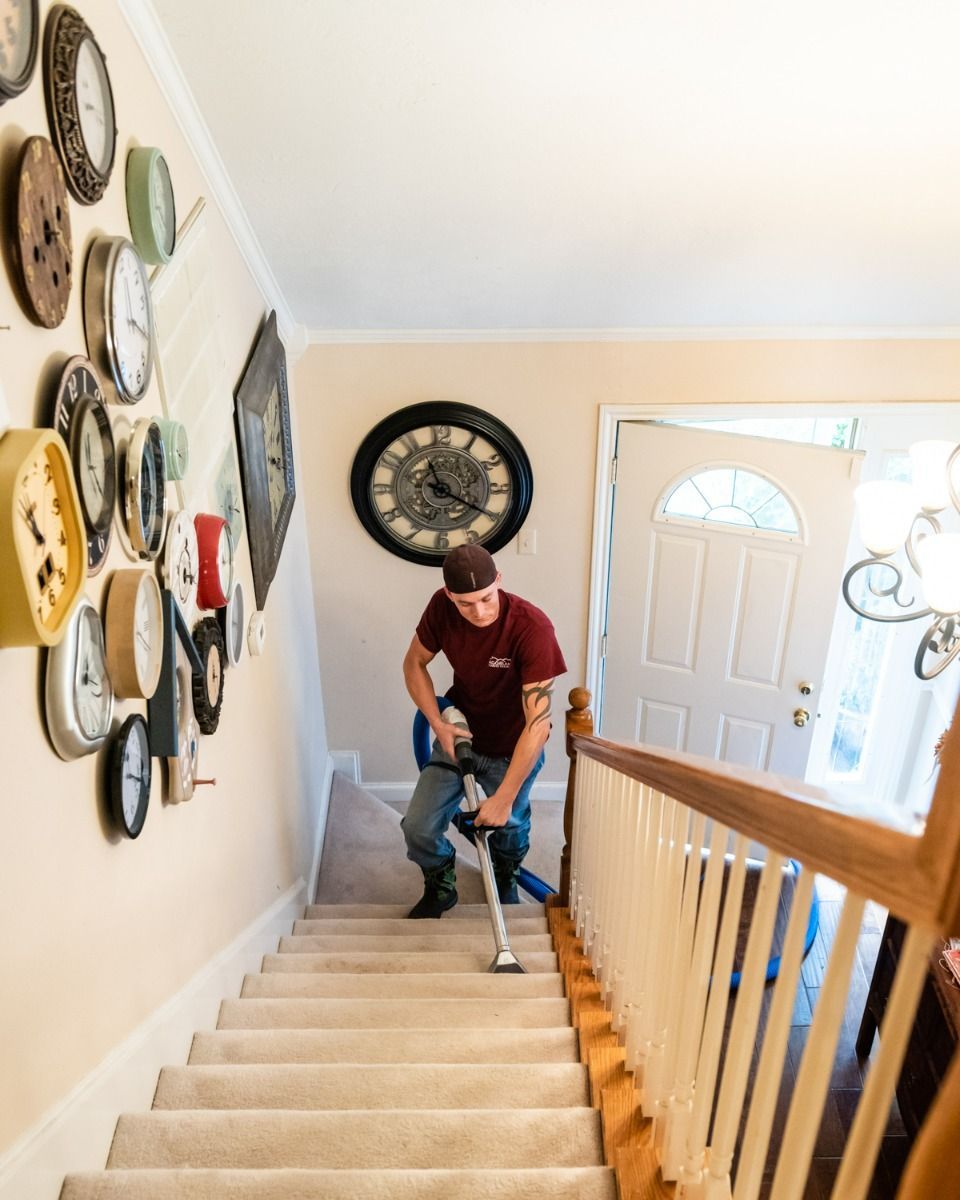 a man is using a vacuum cleaner to clean the stairs in a house .