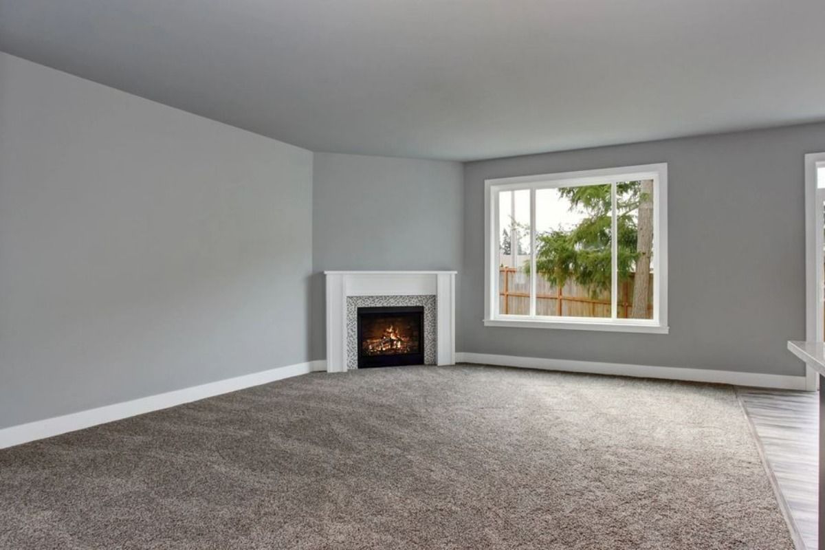 an empty living room with a fireplace and a window .