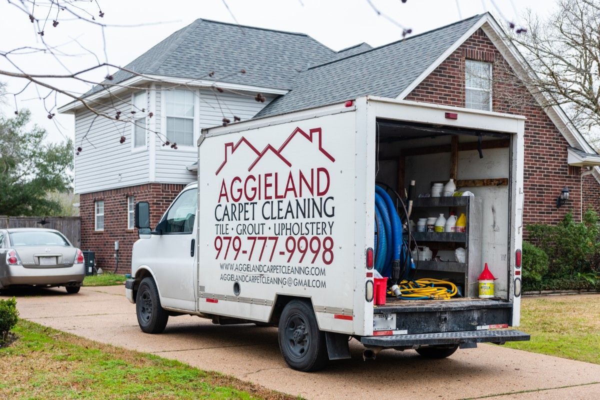a white carpet cleaning truck is parked in front of a brick house .