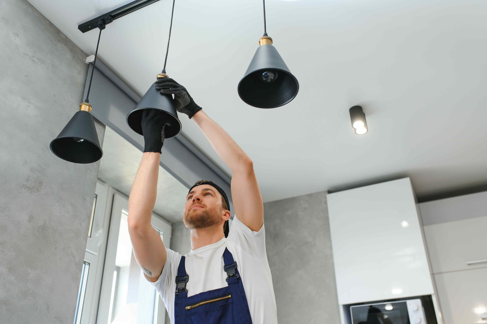 Professional Electrician Installing Hanging Lights In Kitchen
