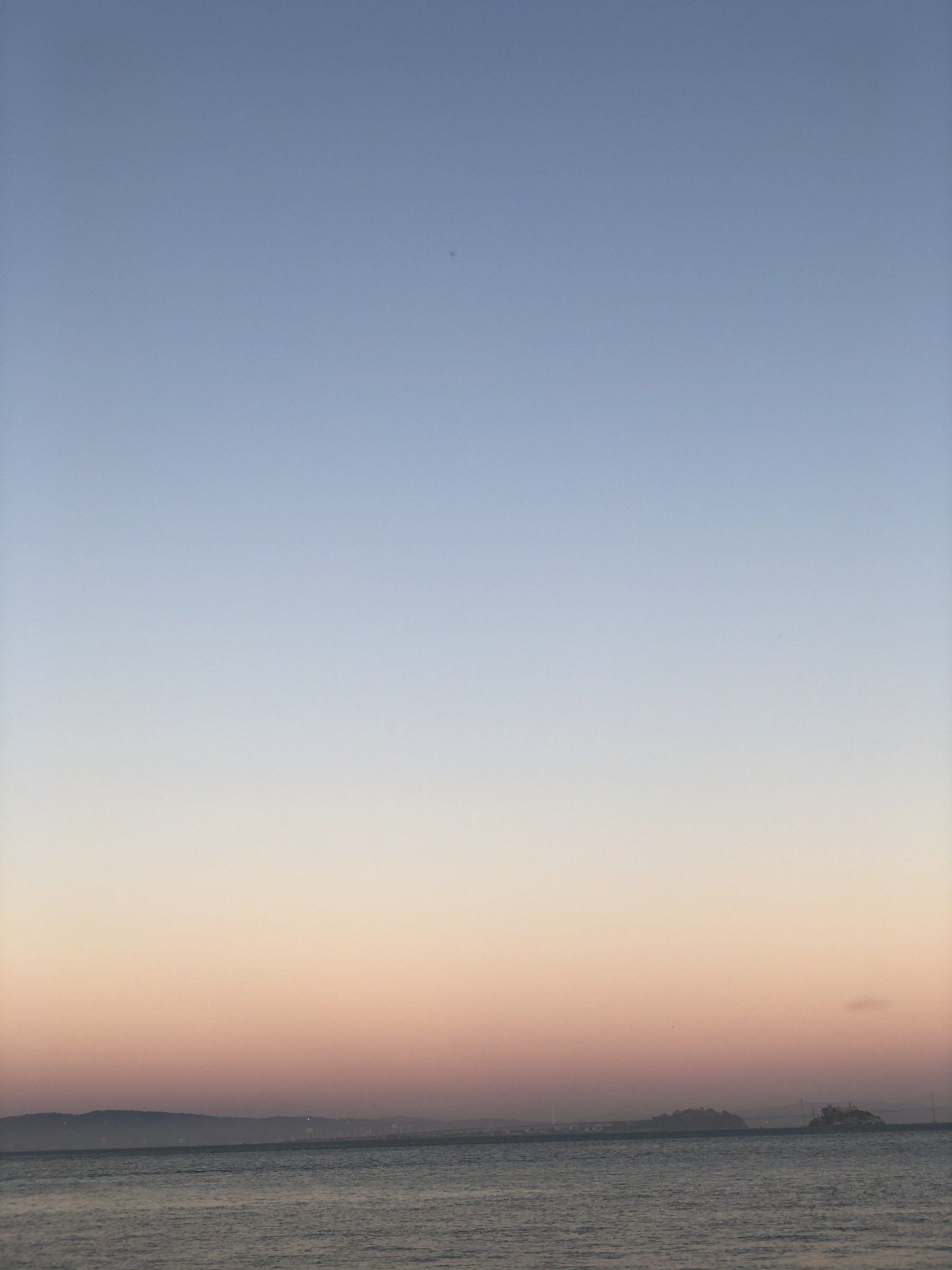 A sunset over a large body of water with mountains in the background.