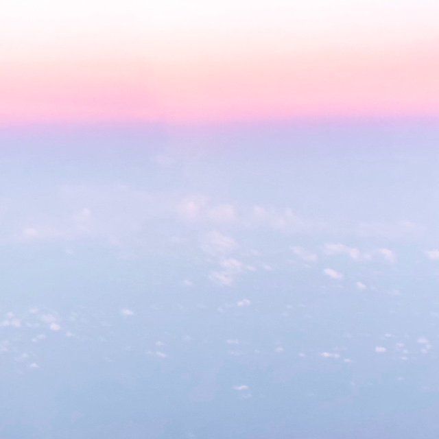 A view of the sky from an airplane window at sunset.