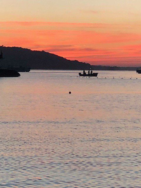 A sunset over a body of water with boats in it