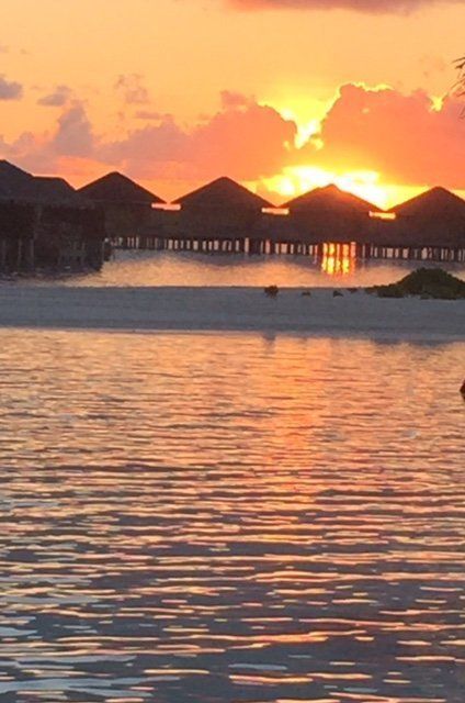 A sunset over a body of water with a row of bungalows in the background