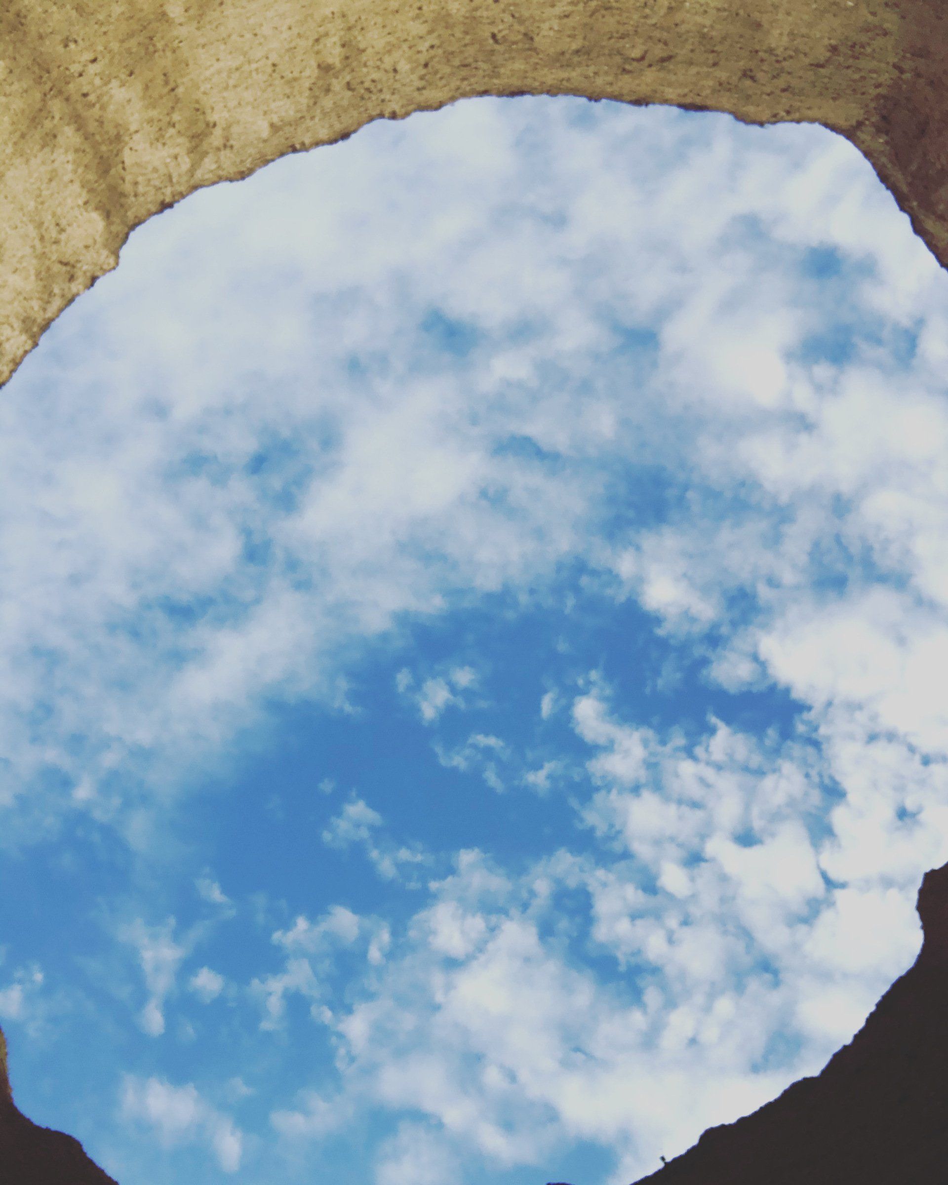 A blue sky with white clouds is reflected in a puddle