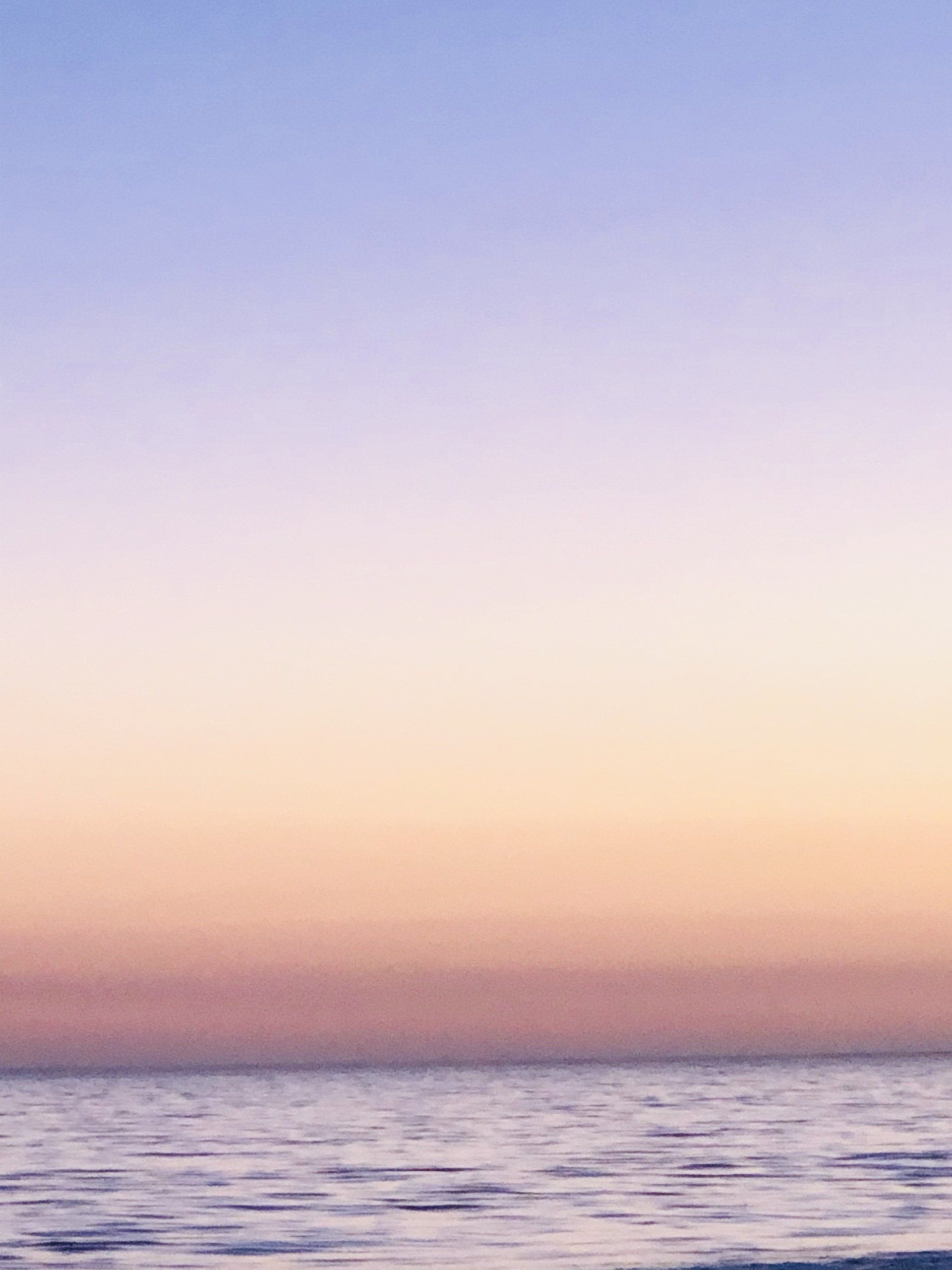 A sunset over the ocean with a purple and pink sky