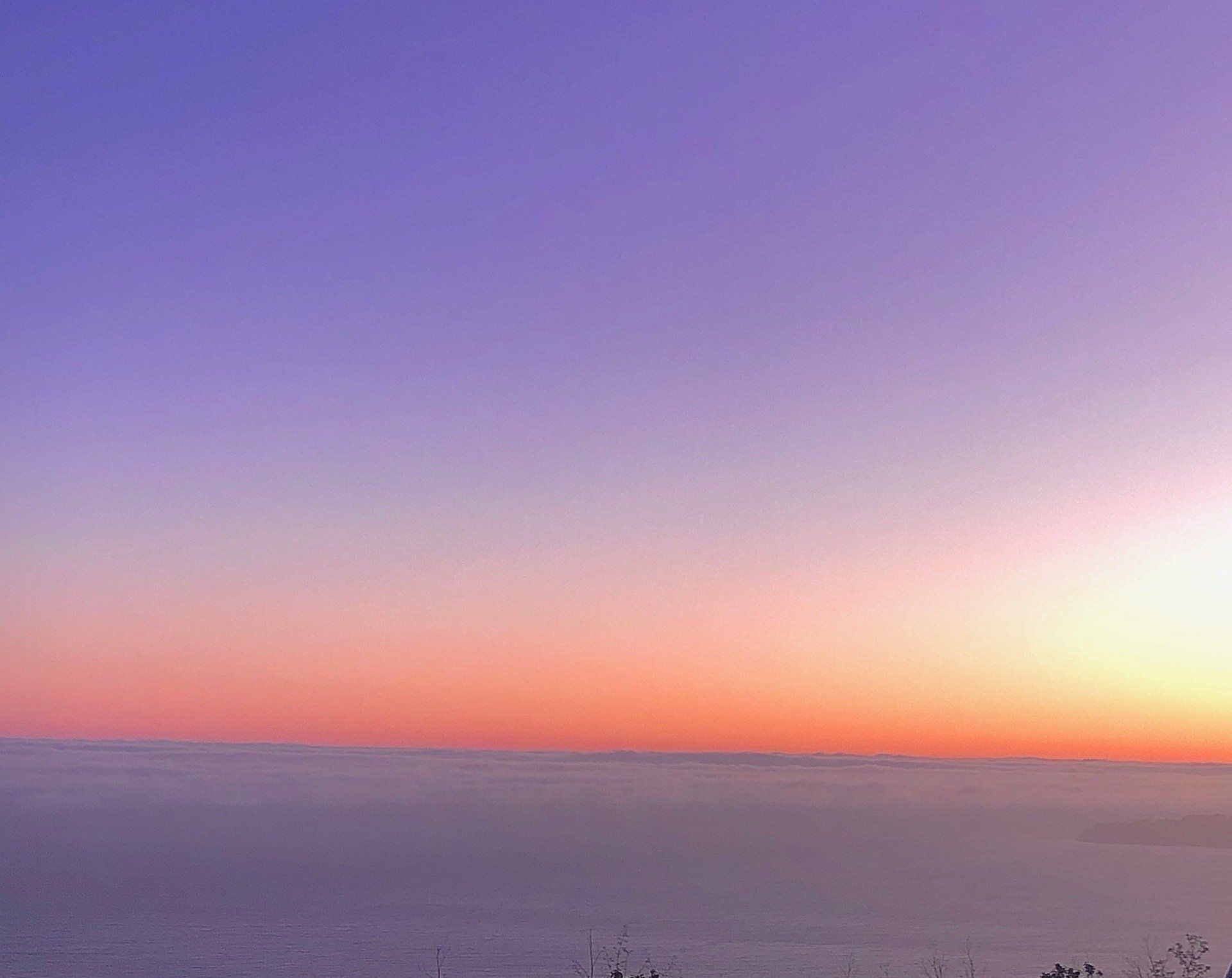 A sunset over the ocean with a purple and orange sky