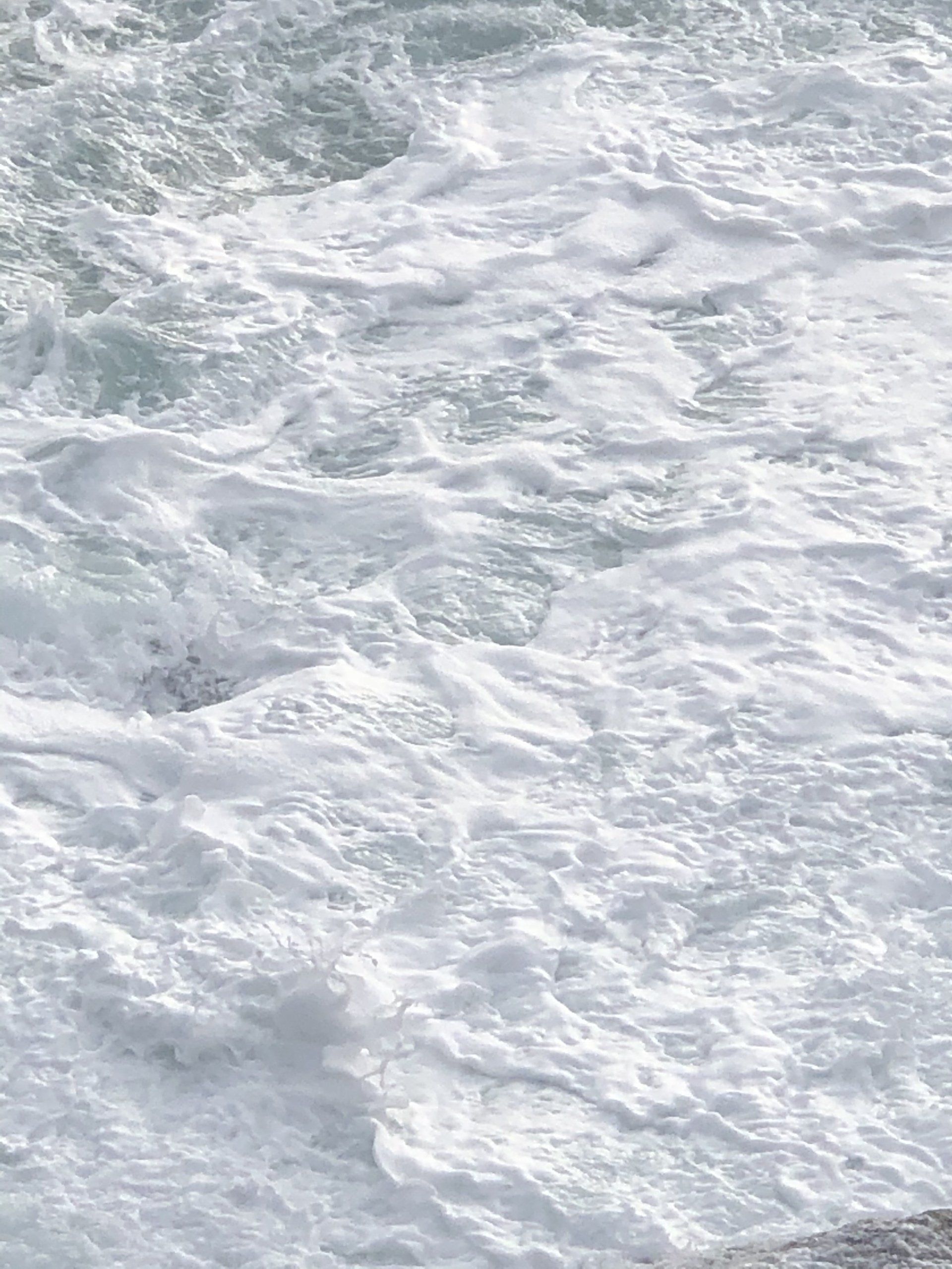 A close up of a body of water with waves crashing on the shore.