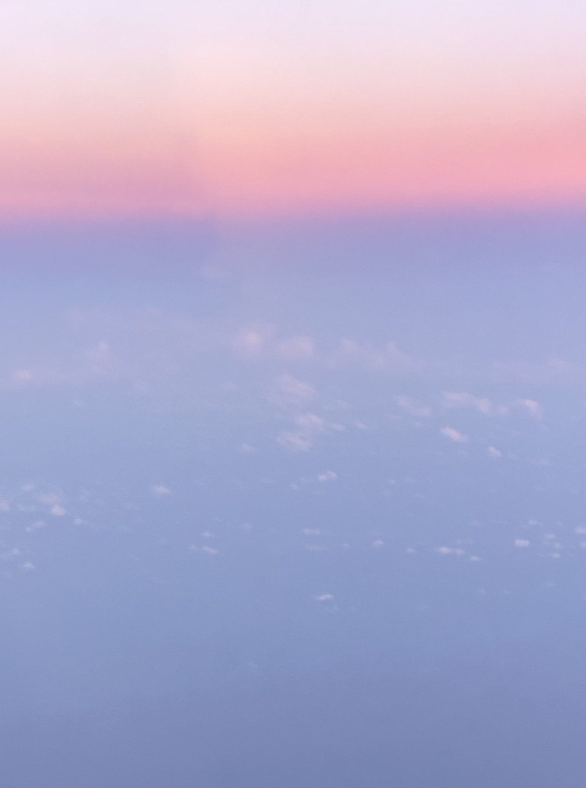 A view of the clouds from an airplane window at sunset.