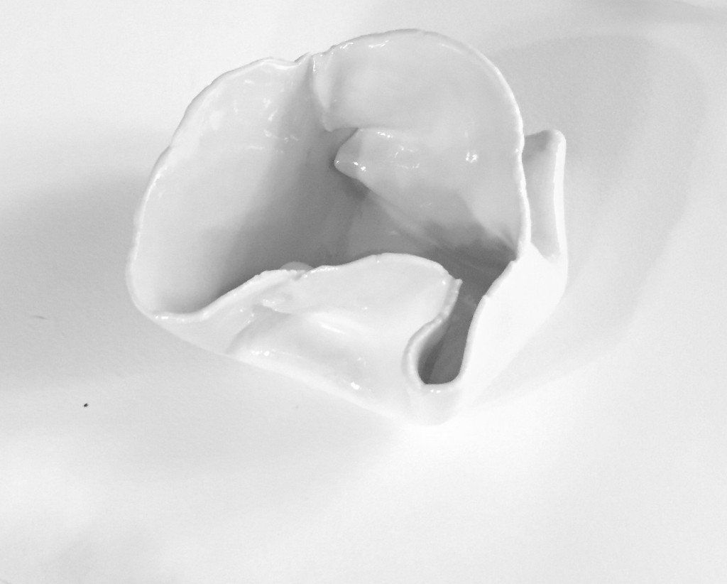 A close up of a white flower shaped vase on a table.