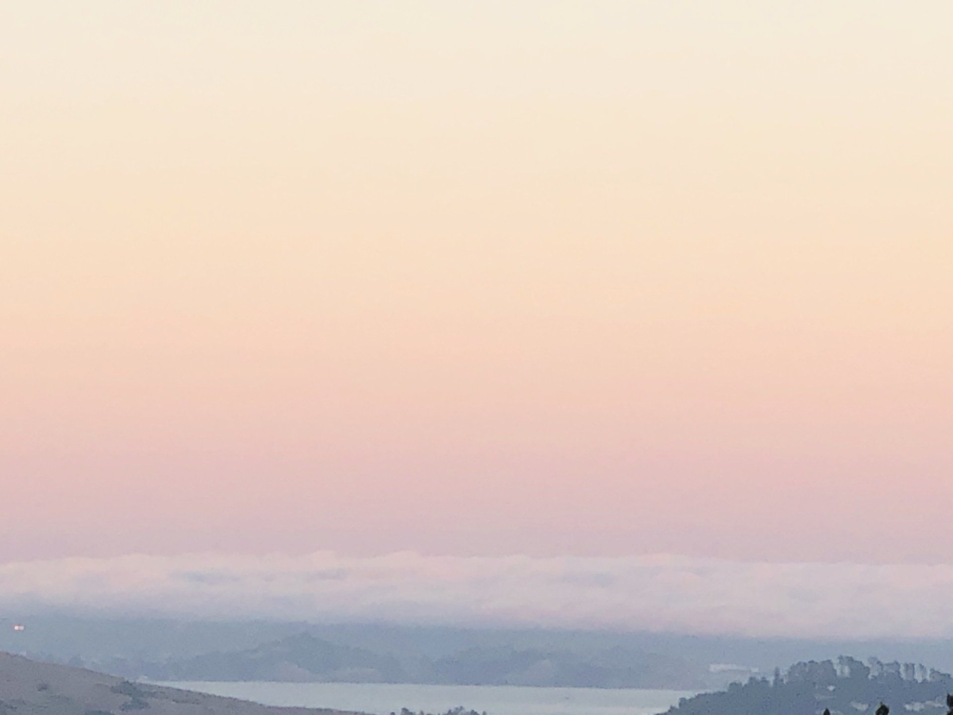 A view of a lake at sunset with a pink sky.