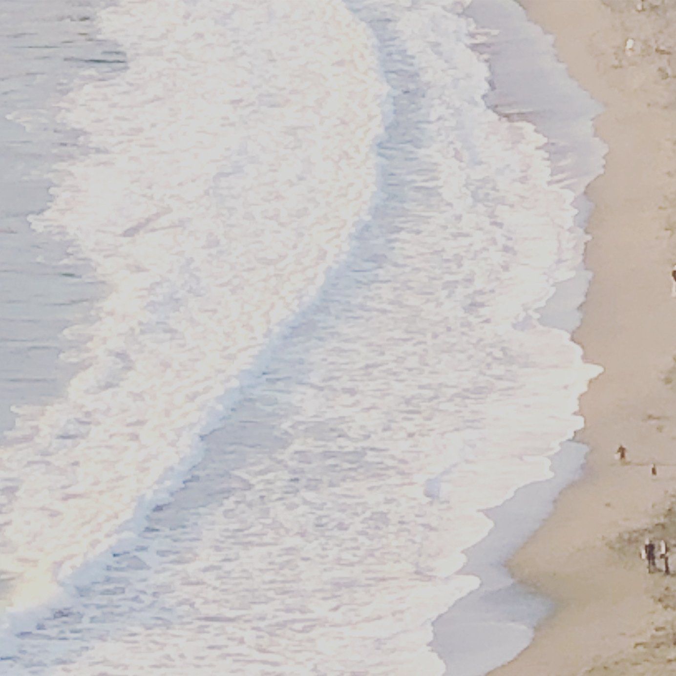 Aerial view of waves crashing on a sandy beach.
