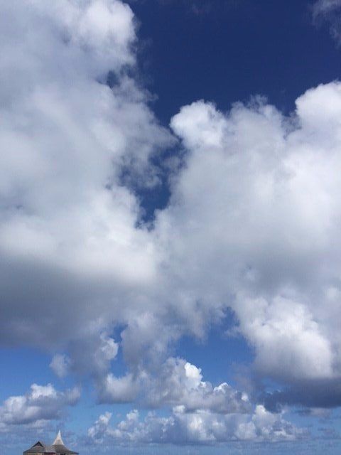 A blue sky with white clouds and a small island in the distance.
