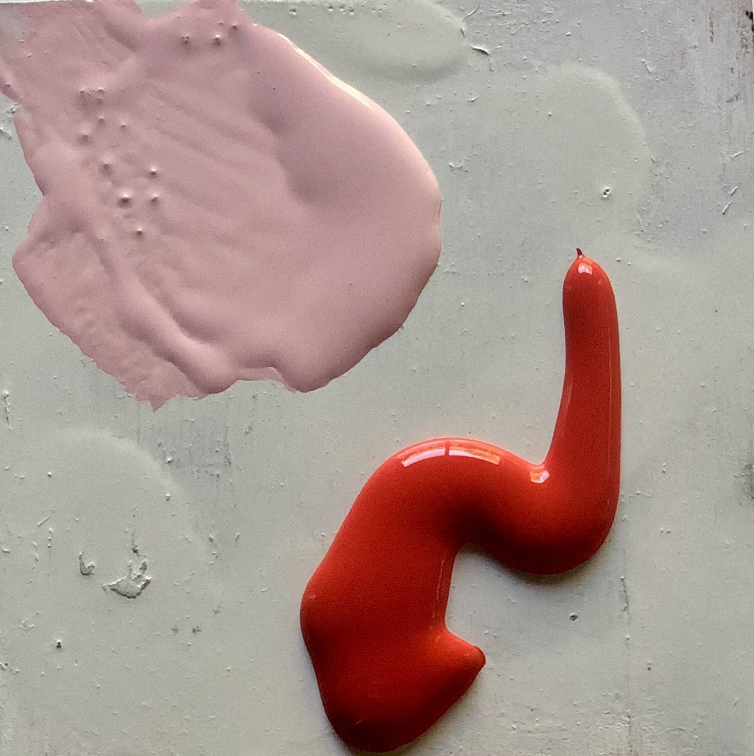 A pink and red swirl of paint on a white surface