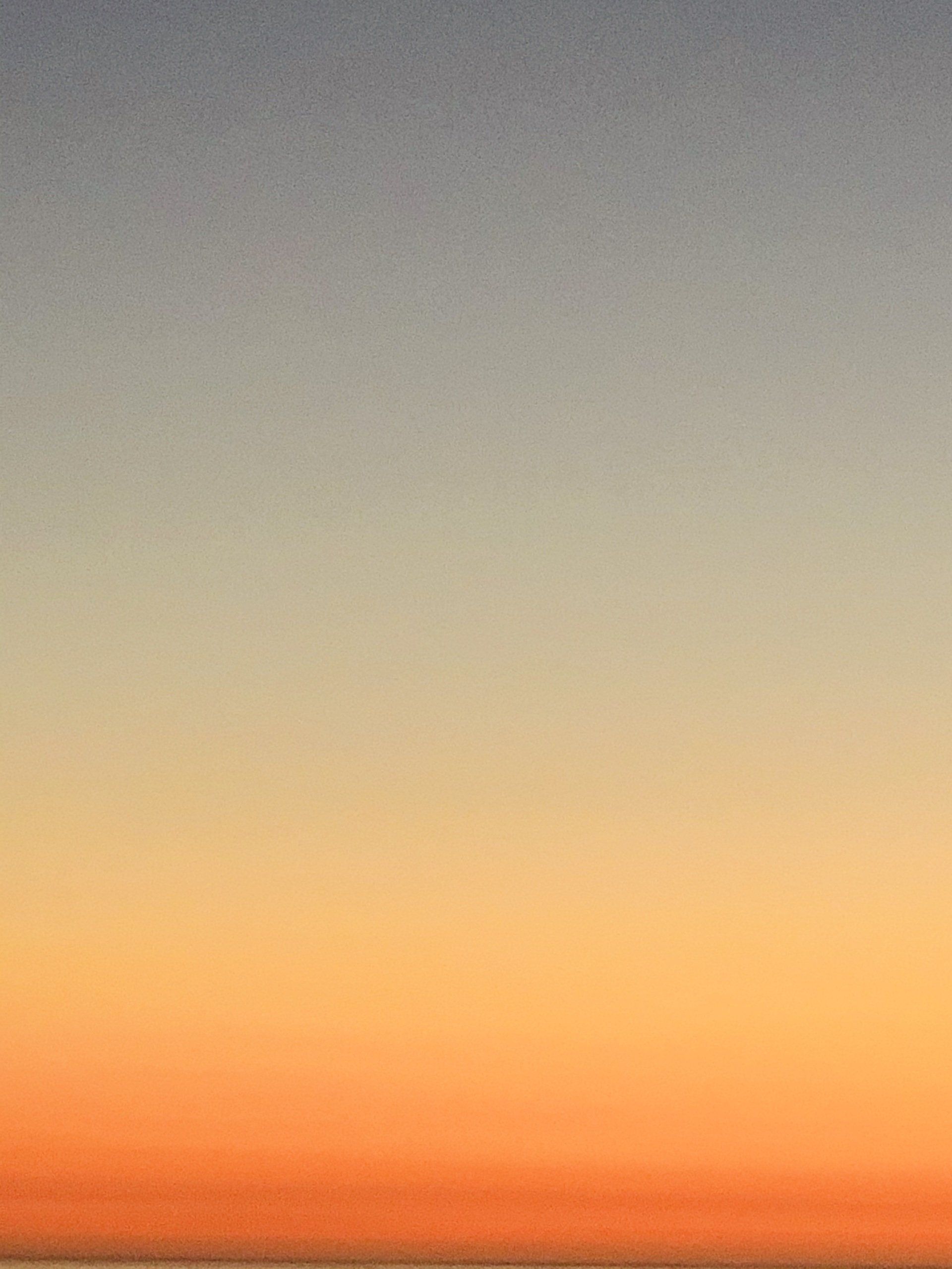 A sunset over a body of water with a gray and orange gradient in the sky.