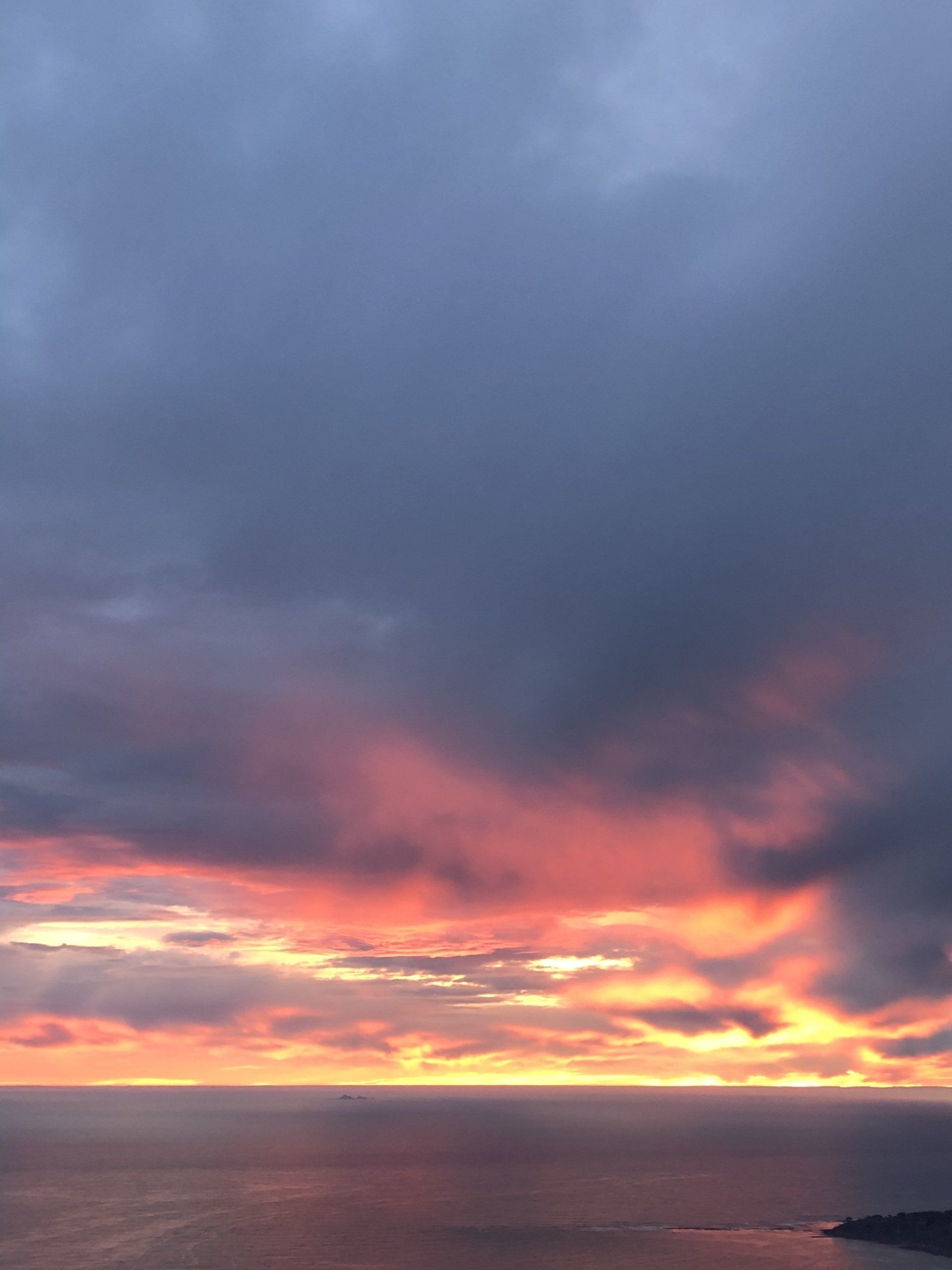 A sunset over the ocean with a cloudy sky
