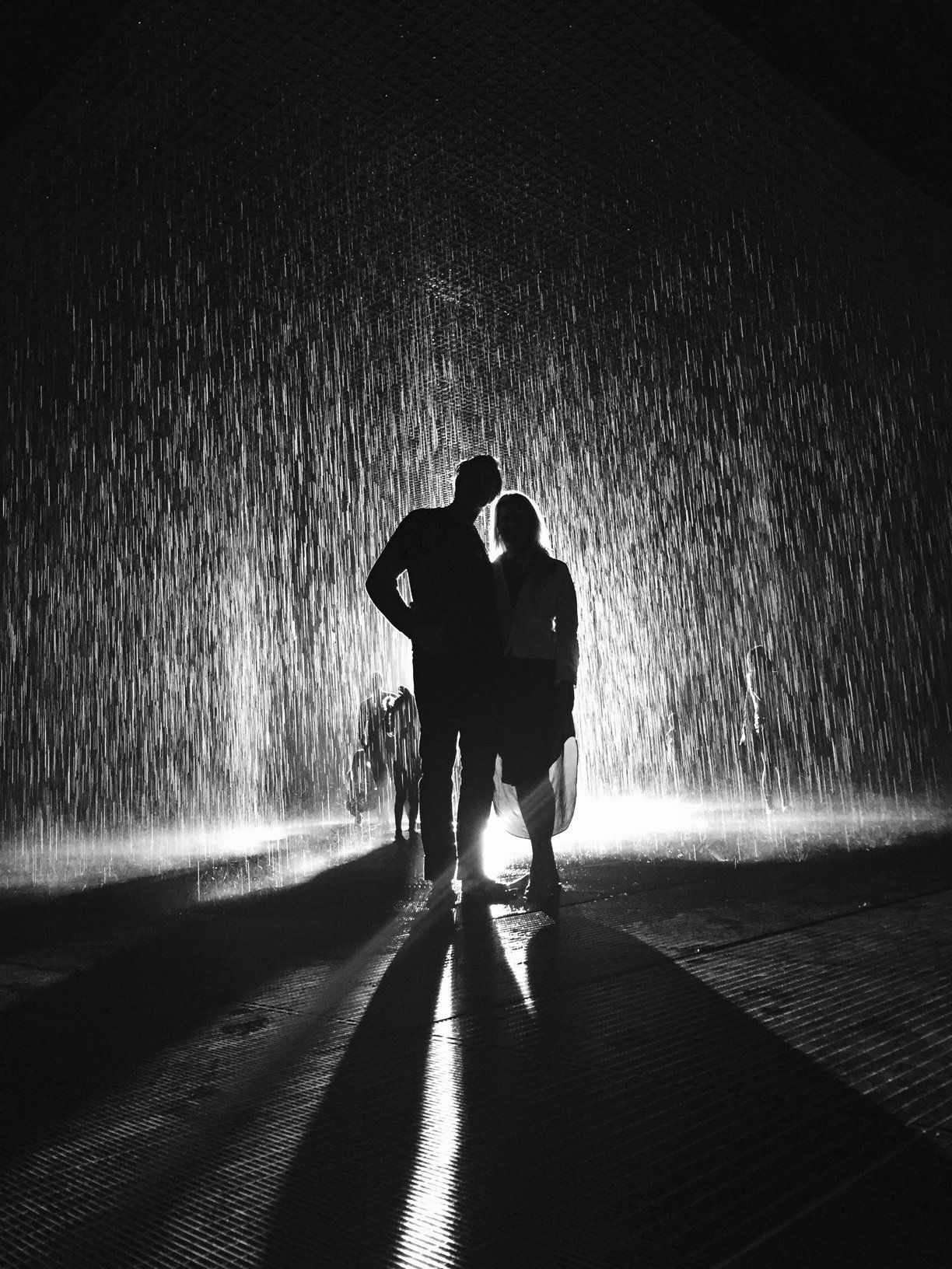 A couple standing in the rain with their shadows on the ground