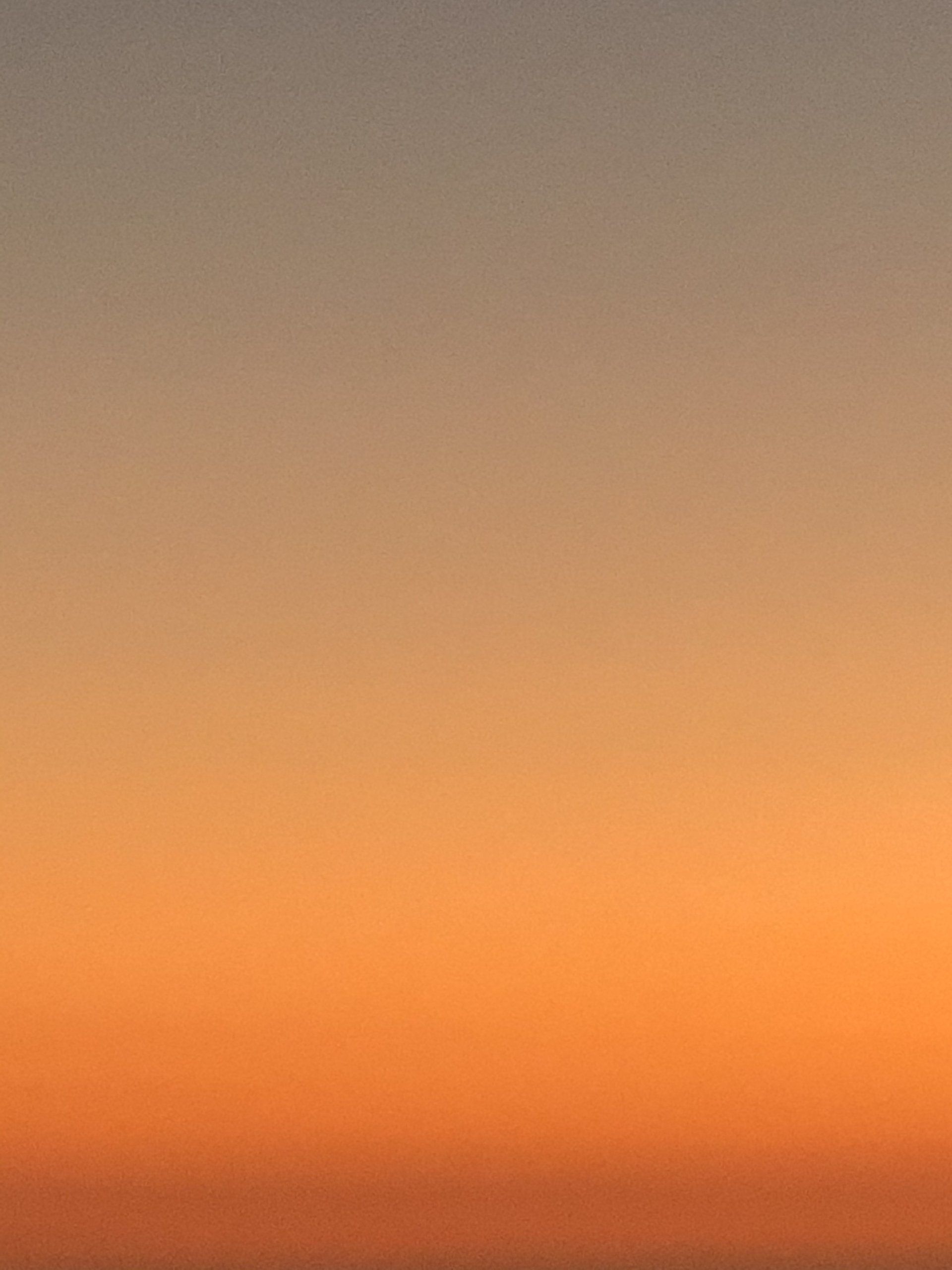 A sunset with a gradient of orange and gray in the sky