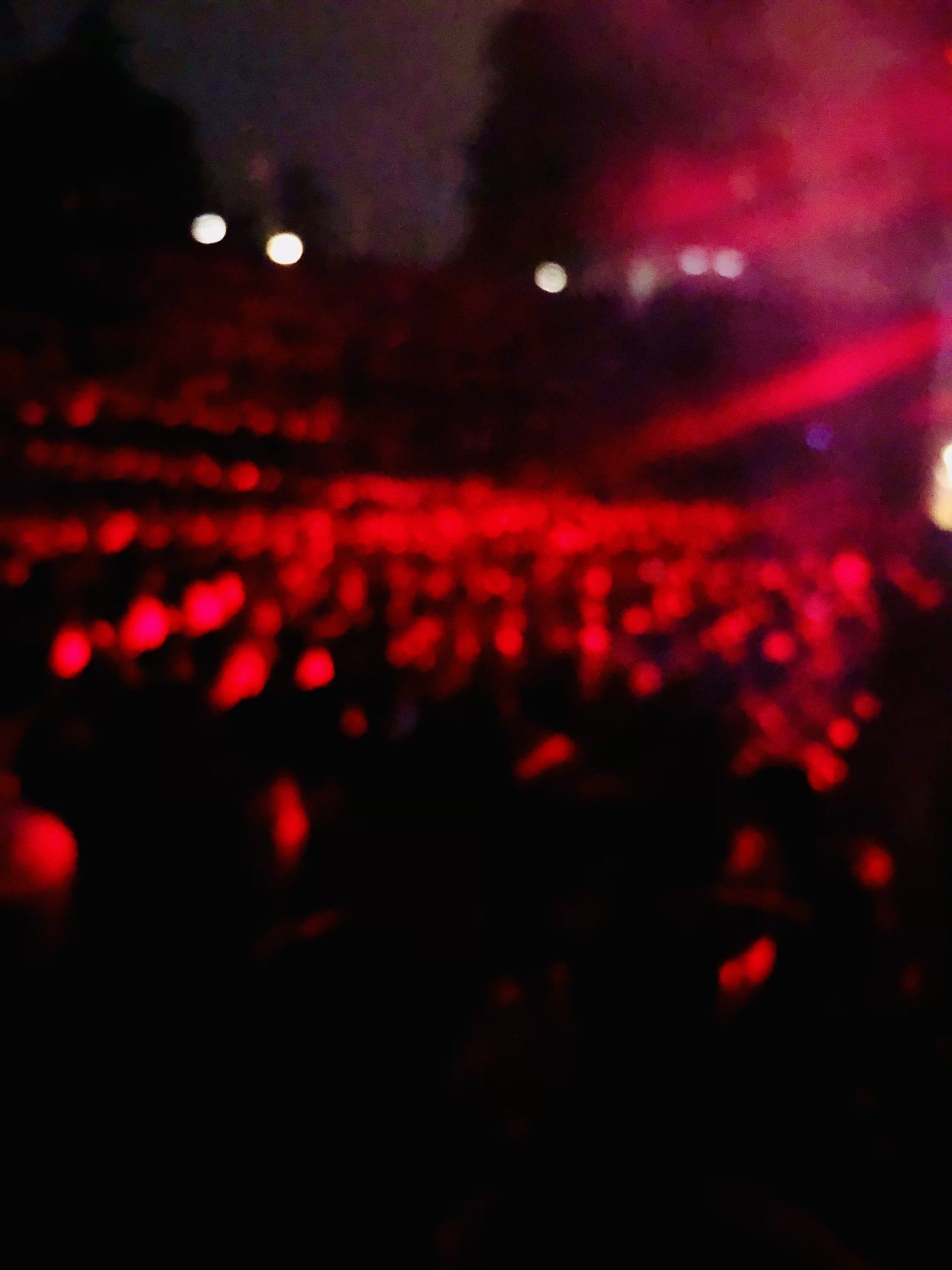 A blurry picture of a crowd at a concert with red lights