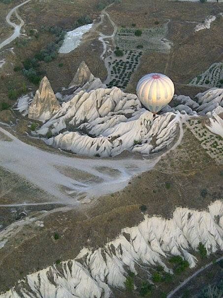 An aerial view of a hot air balloon flying over a rocky area