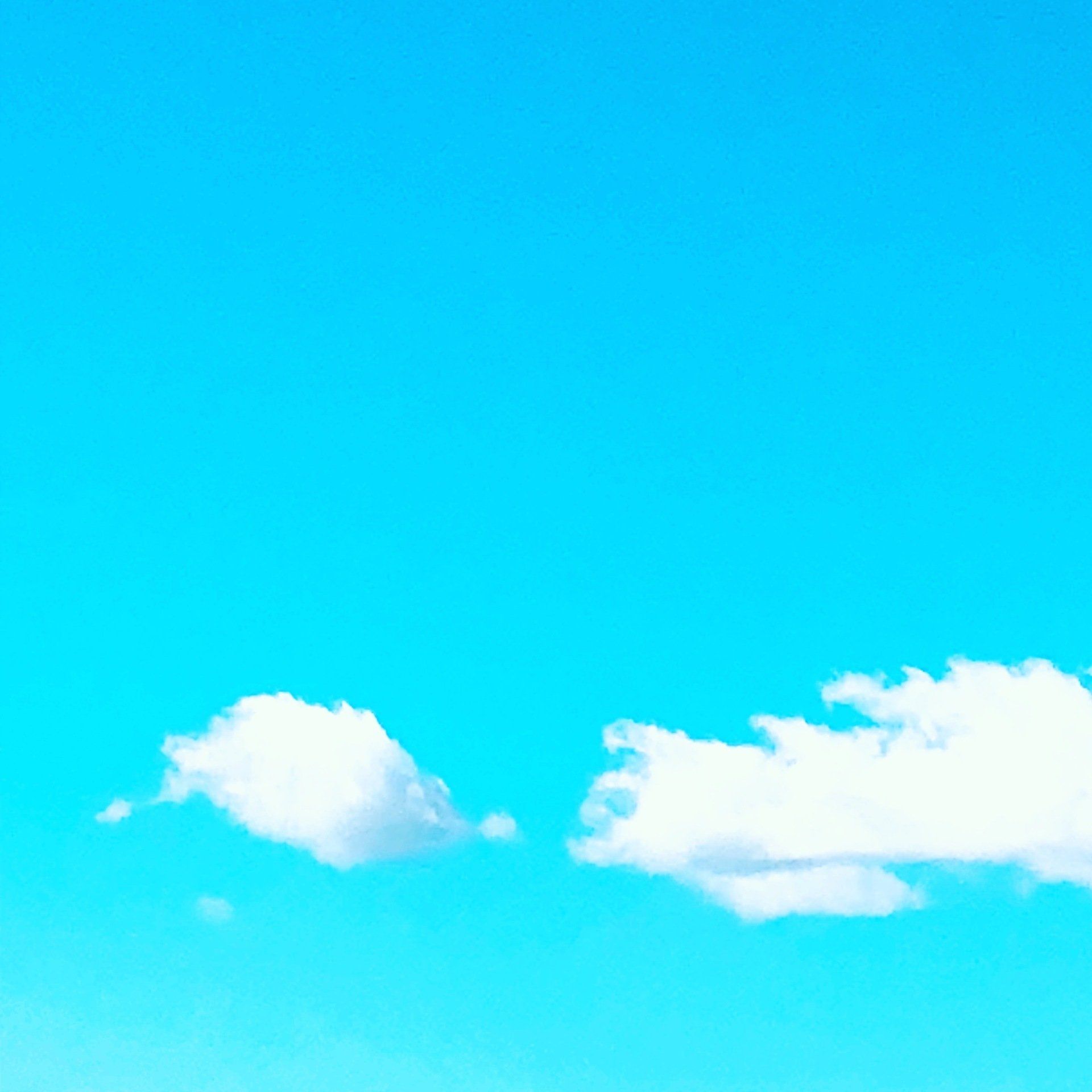 Two white clouds are floating in a blue sky.
