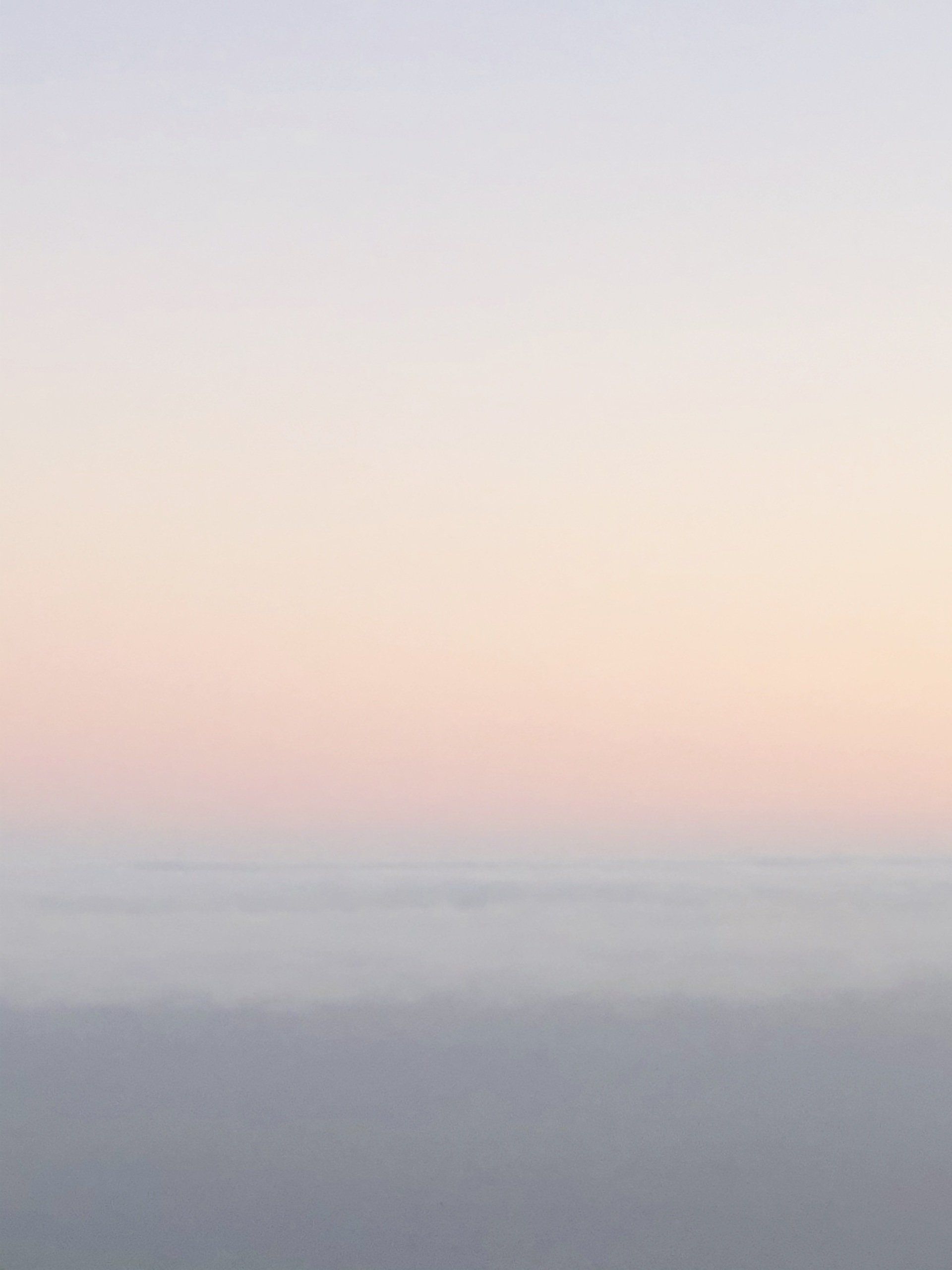 A sunset over the ocean with a gray sky and a few clouds