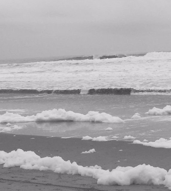A black and white photo of waves crashing on a beach