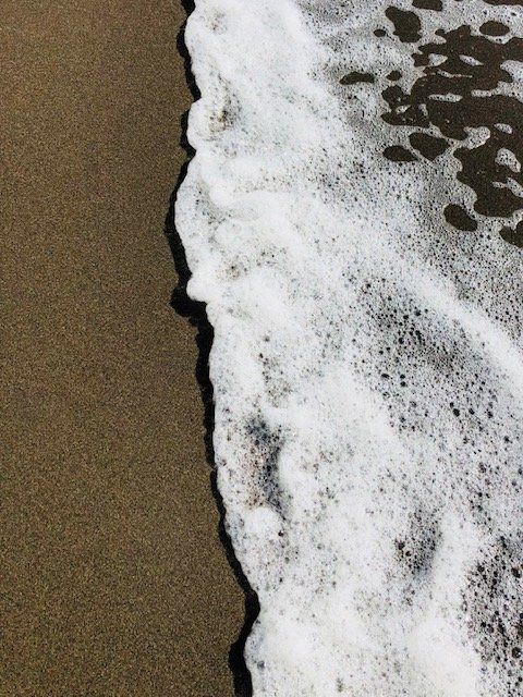 A close up of a wave on a sandy beach