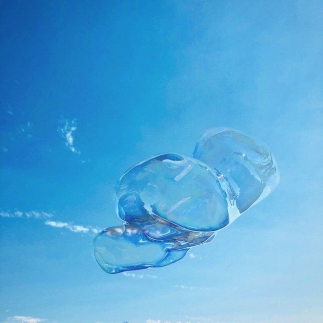 A blue plastic bottle is floating in the air against a blue sky.
