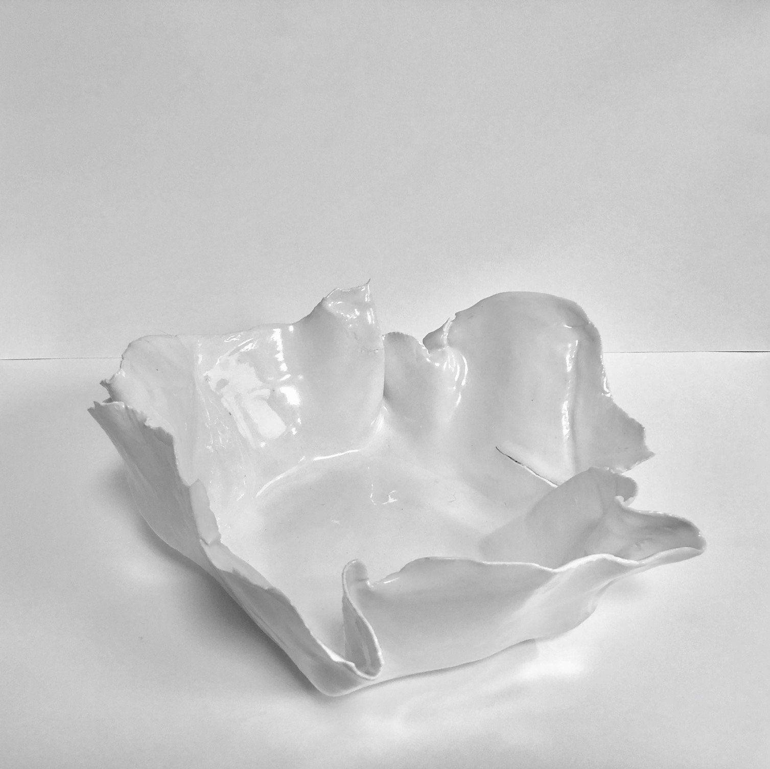 A white ceramic bowl is sitting on a white table.