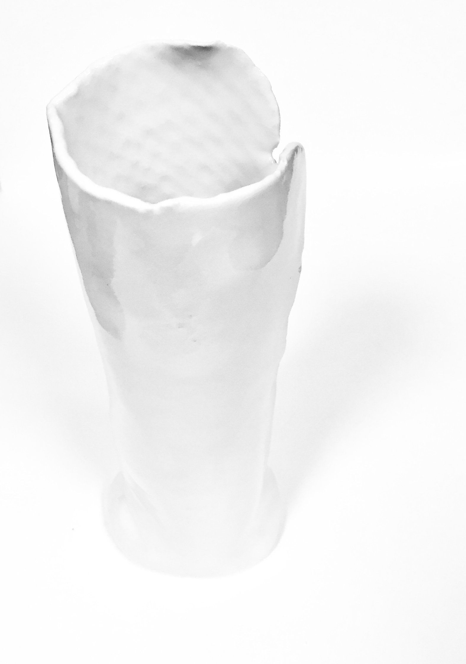 A white vase is sitting on a white surface.