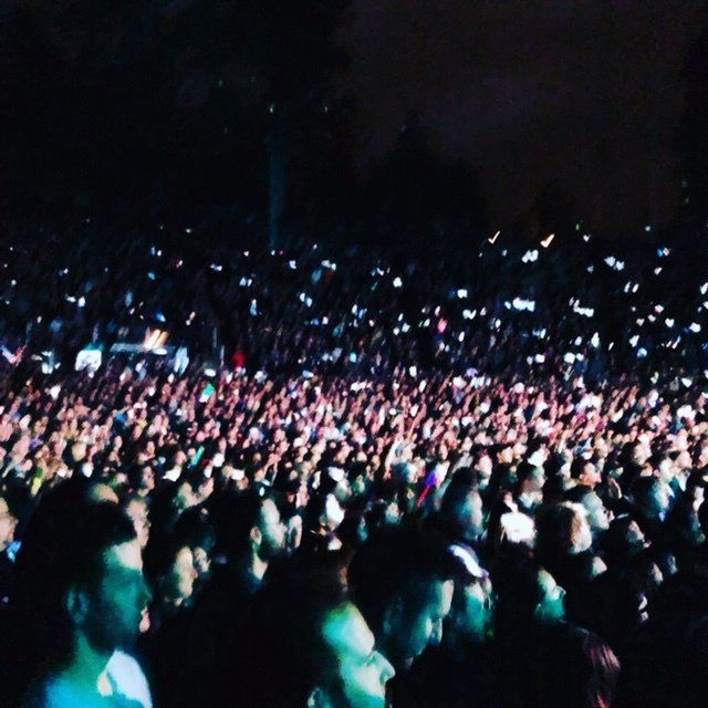 A crowd of people are gathered at a concert at night
