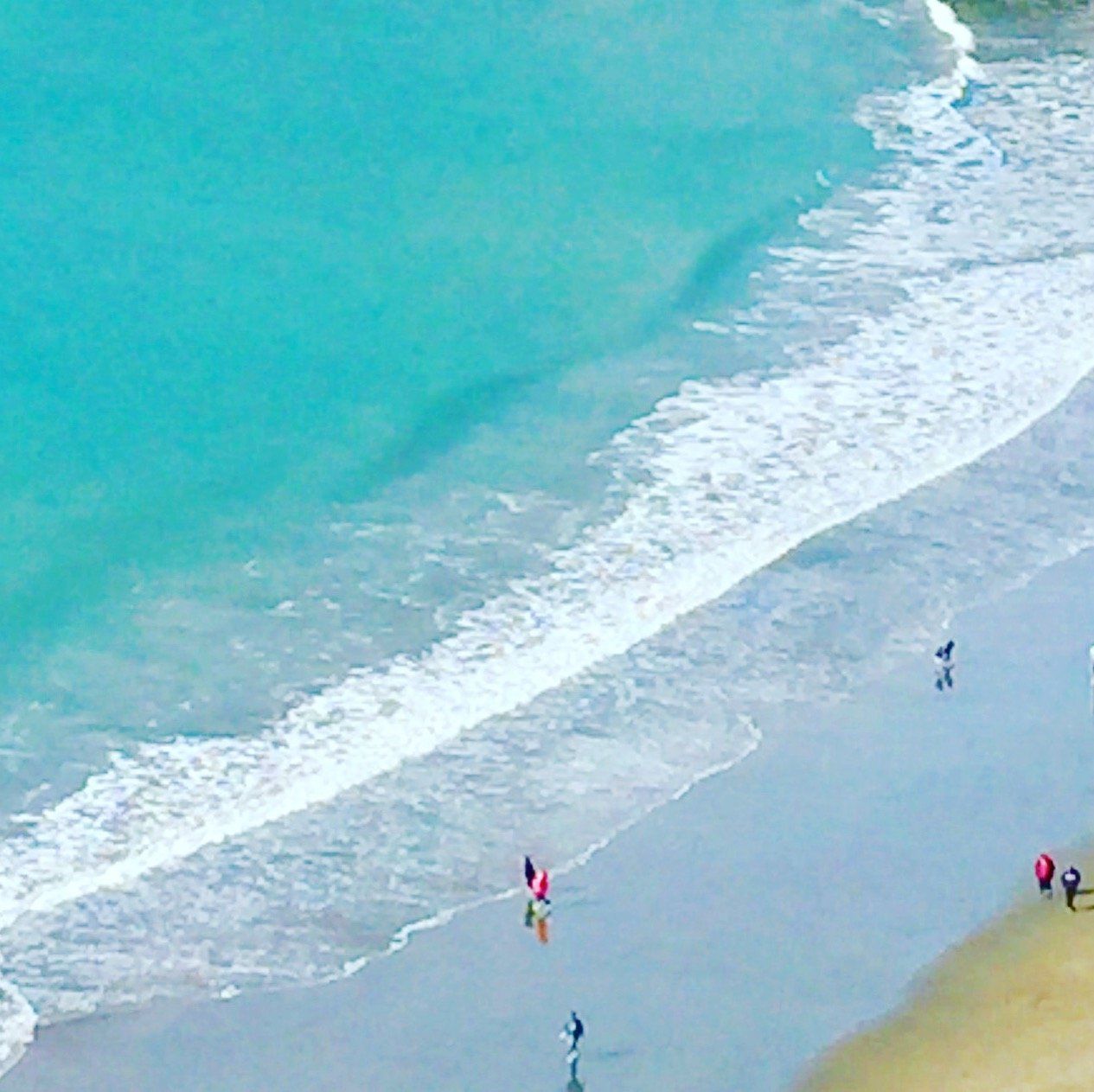An aerial view of a beach with people walking on it
