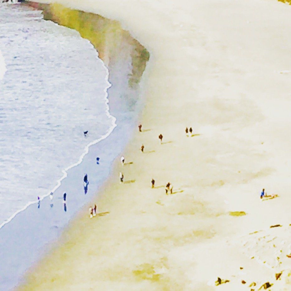 A group of people are walking on a beach near the ocean