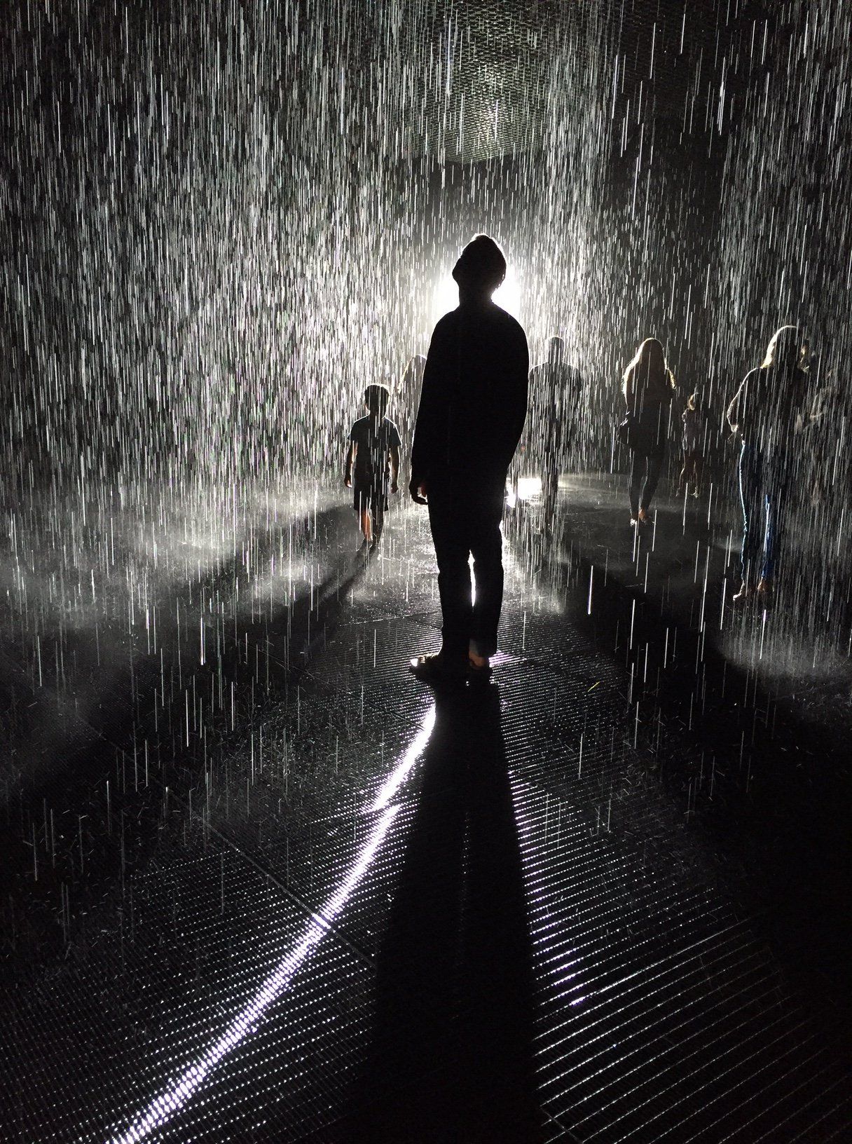 A man is standing in the rain in a dark room