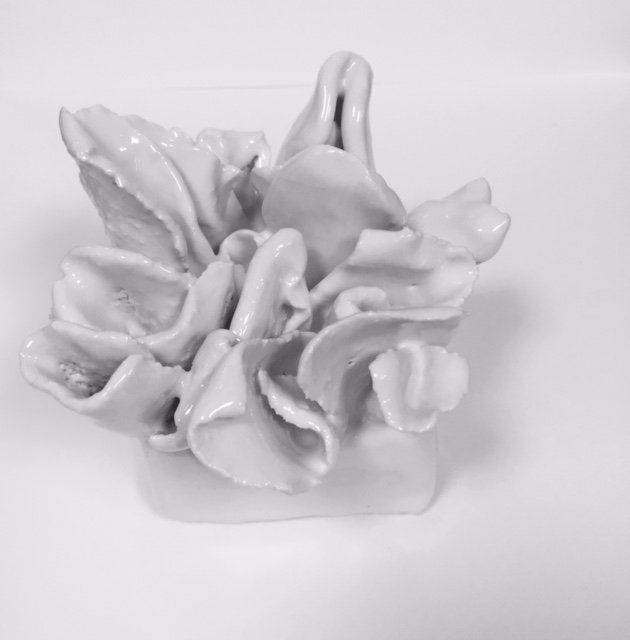 A white ceramic flower is sitting on a white surface.