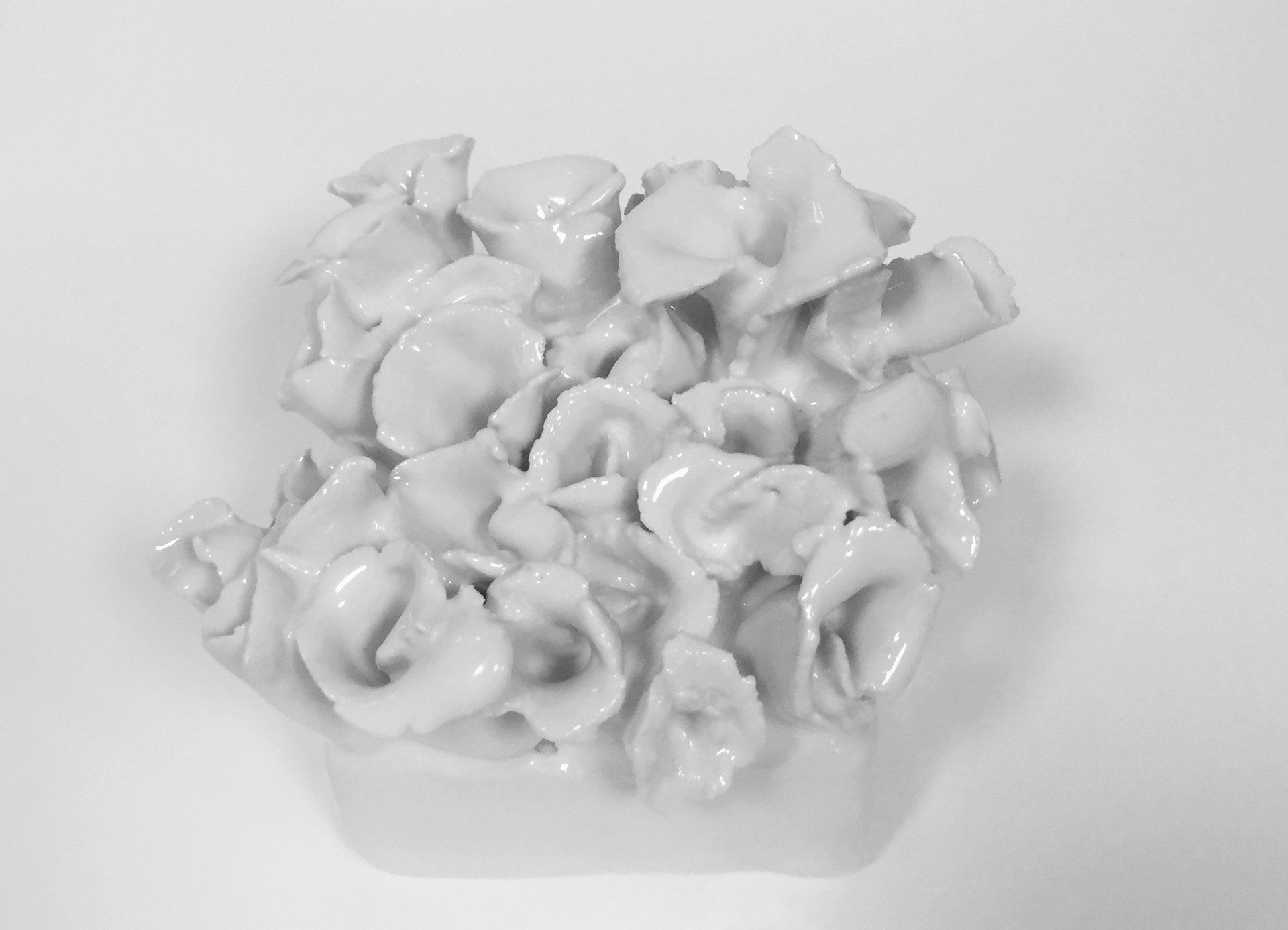 A black and white photo of a white ceramic sculpture on a white surface.