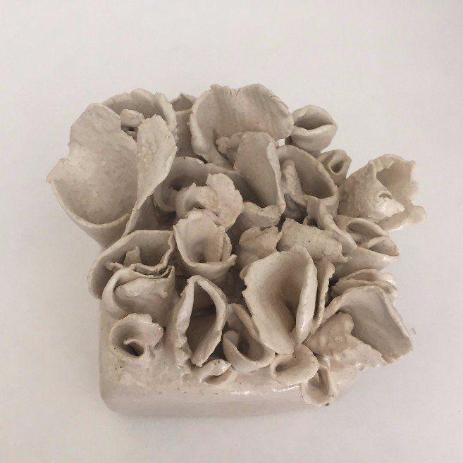 A white ceramic sculpture with a lot of flowers on it