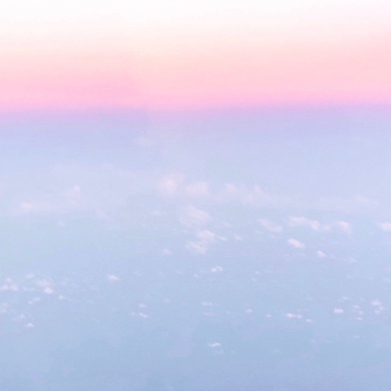 A view of the clouds from an airplane window at sunset.