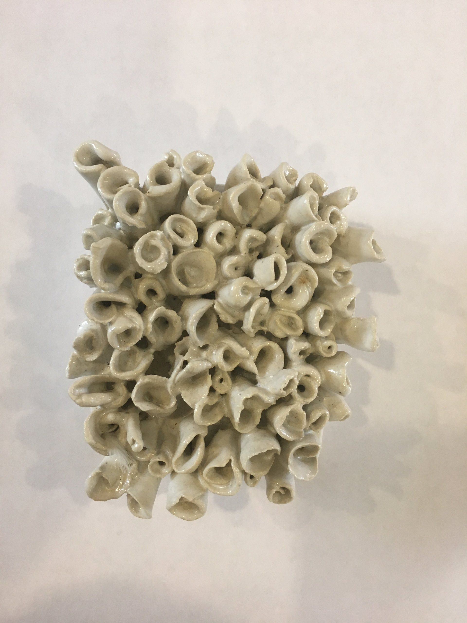 A close up of a white ceramic sculpture on a white surface.