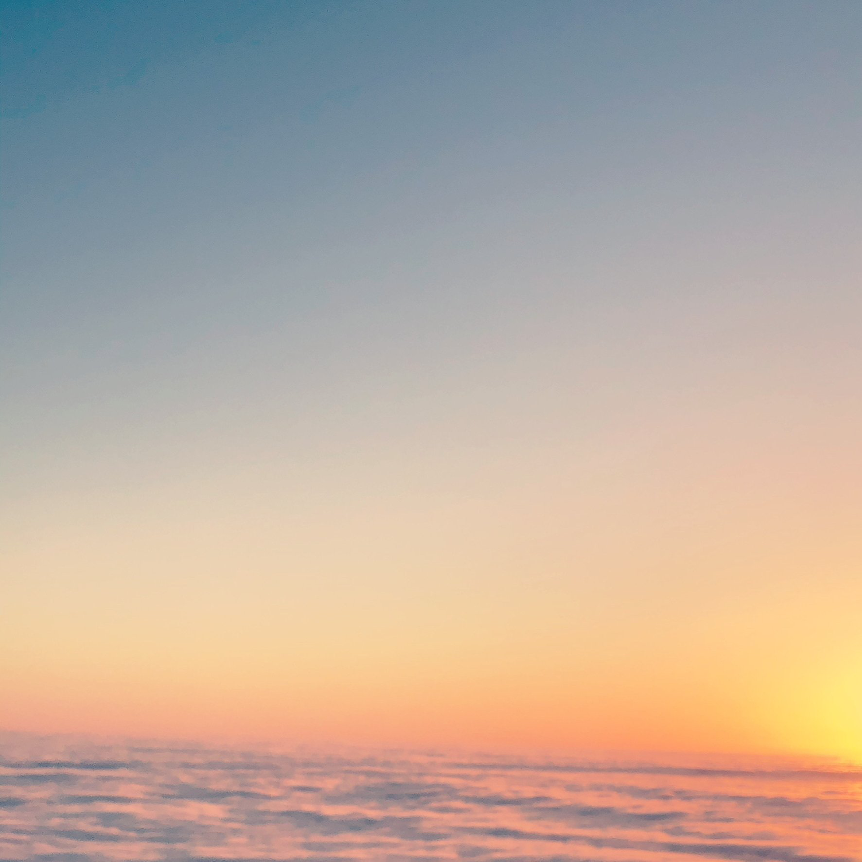 The sun is setting over the clouds in the sky.