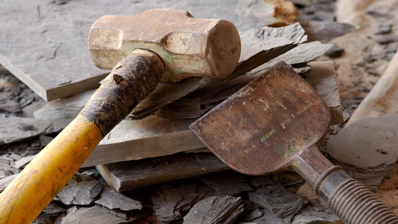 “Masonry trowel and hammer resting on a job site surface for block and retaining wall construction”